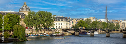 Panoramic view of the Pont des Arts in Paris with the Eiffel Tower under a blue sky and over a beautiful Seine River that divides the Parisian city in two, creating a beautiful contrast and beautiful.