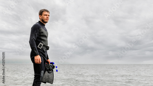 Fototapeta Naklejka Na Ścianę i Meble -  Portrait of a male diver in a wetsuit and diving mask. Freediving. Summer holidays at the sea. The concept of a strong-willed and determined person