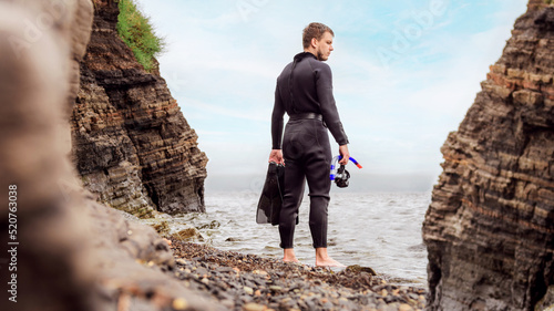 Obraz na plátně a diver in a wetsuit stands on the seashore