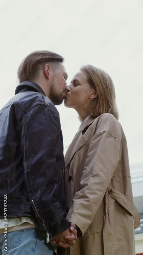 Young couple of European appearance are walking street holding hands and kissing Young couple of European appearance are walking street holding hands and kissing