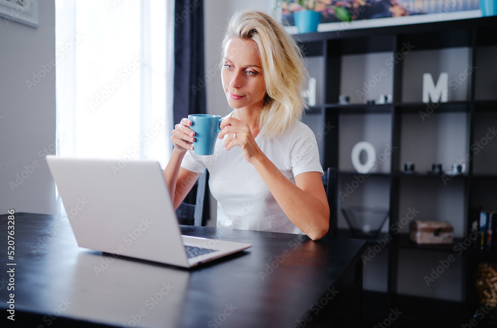 Working at home. Young woman using laptop computer while sdrinking coffee. Working at home. Young woman using laptop computer while sdrinking coffee.