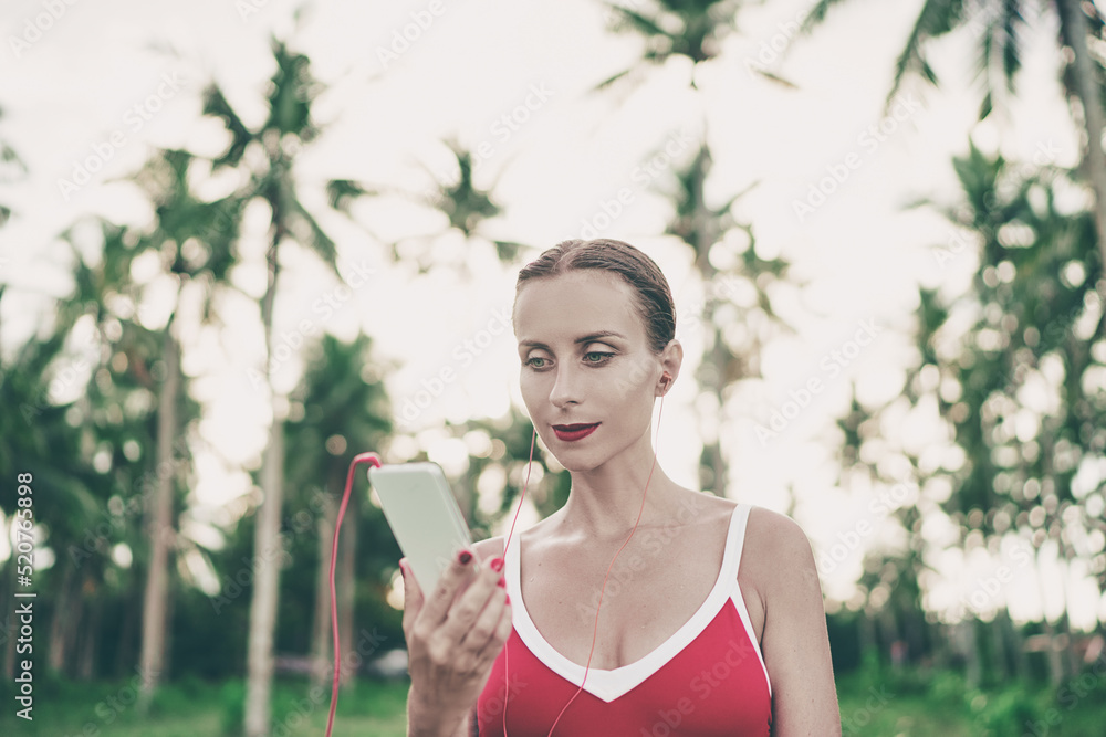 Enjoying the sound. Happy young woman with earphones listening music on smartphone. Tropical vacation. Enjoying the sound. Happy young woman with earphones listening music on smartphone. Tropical vacation.
