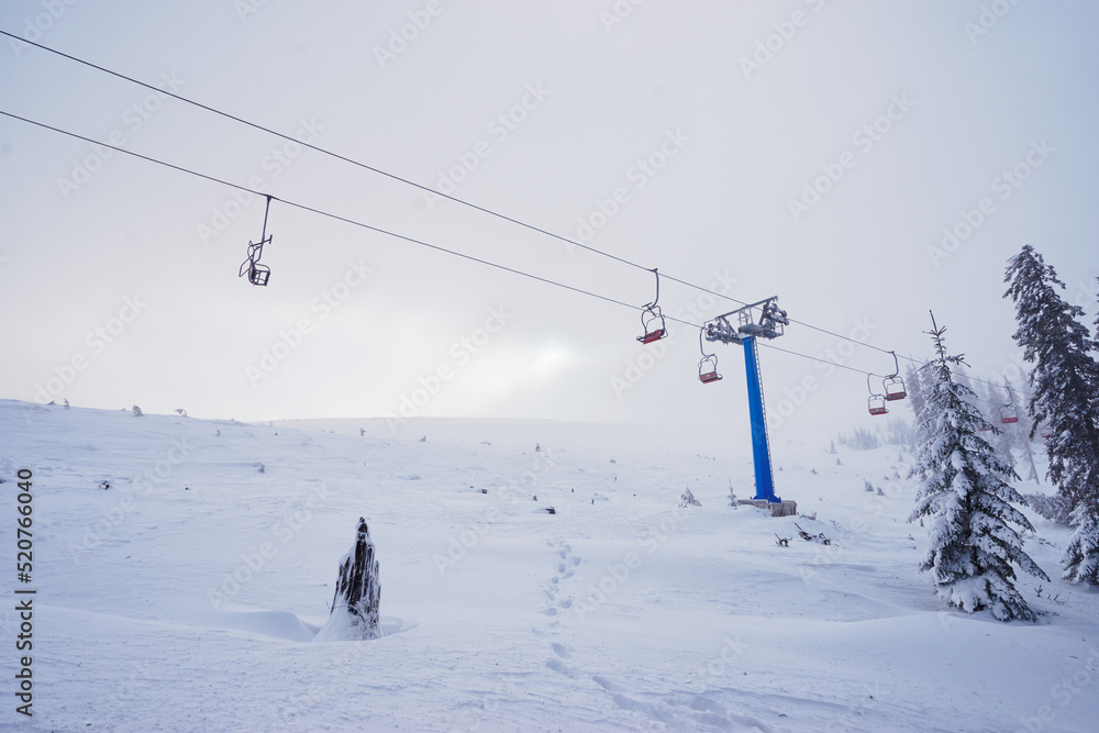 Ski lift with seats going over the mountain and paths from skies and snowboards. Ski lift with seats going over the mountain and paths from skies and snowboards.
