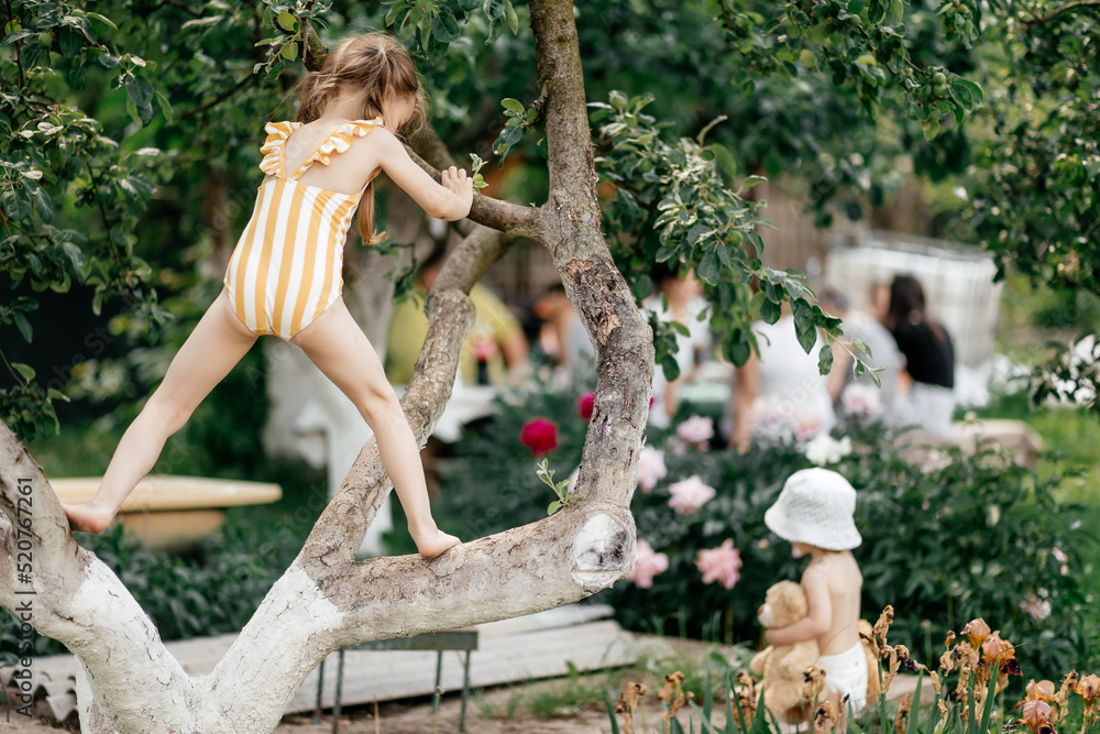 Small girl climb tree in summer garden, activity. Little girl on tree branch, childhood. Vacation, activity, lifestyle. Kid fashion, style, beauty Childhood youth growth Small girl climb tree in summer garden, activity. Little girl on tree branch, childhood. Vacation, activity, lifestyle. Kid fashion, style, beauty Childhood youth growth