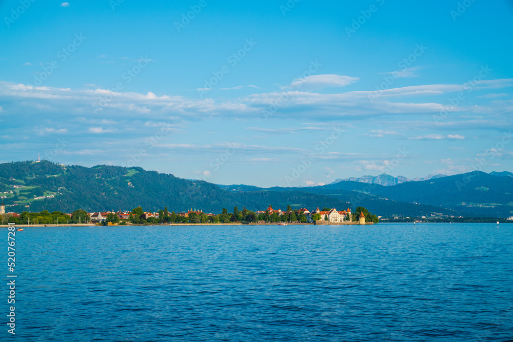 Germany, Lindau city houses at lakeside of bodensee lake in warm sunset sunlight in summer, panorama view to alps mountains