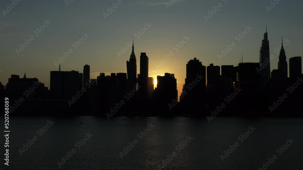 very slow tilting shot across the rare Manhattanhenge phenomenon with a sun ray appearing from between buildings then disappearing again very slow tilting shot across the rare Manhattanhenge phenomenon with a sun ray appearing from between buildings then disappearing again