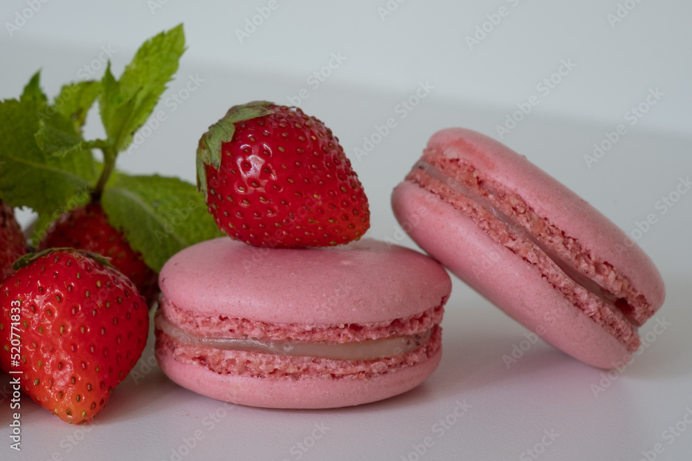 Mix of appetizing pink macarons and fresh strawberries on white background Mix of appetizing pink macarons and fresh strawberries on white background