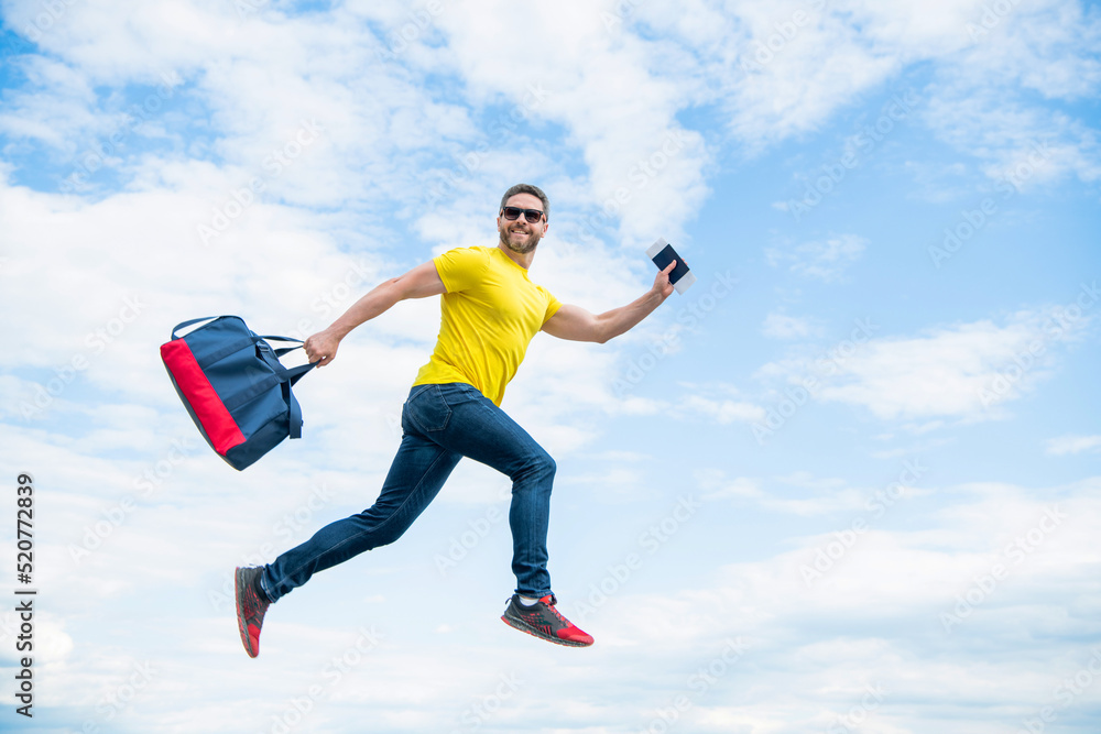 Energetic man running with travel bag midair sky background, vacation Energetic man running with travel bag midair sky background, vacation