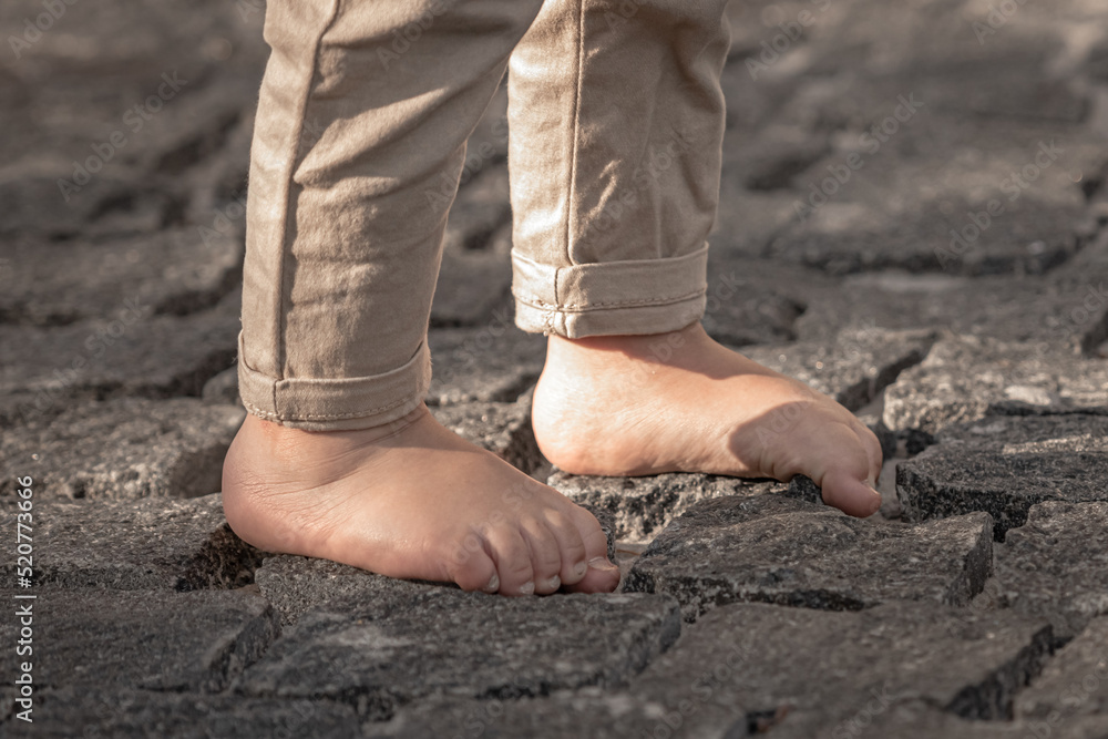 Bare children's feet on the cobblestones. The child is barefoot