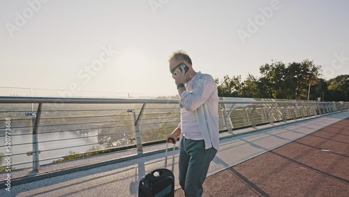 Senior man talks to friend on phone riding electric unicycle photo