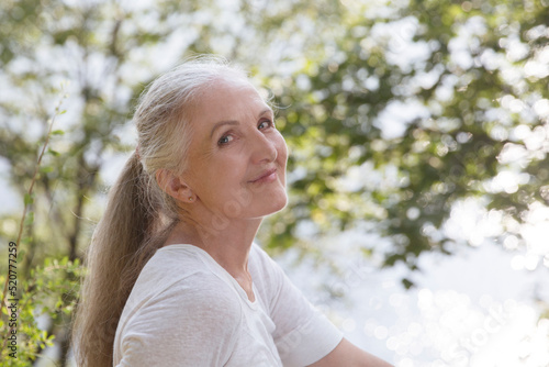 Summer lifestyle portrait smiling senior woman looking at camera relaxed outdoors. Enjoying the little things. spends time in nature in summer. 