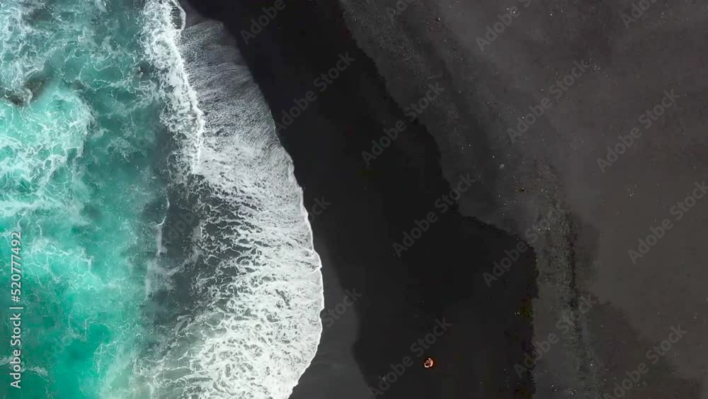 Blaues Meer und schwarzer Strand mit der Drohne gefilmt. Ein Pärchen läuft am schwarzen Strand entlang. Vogelperspektive am Strand. 1 Blaues Meer und schwarzer Strand mit der Drohne gefilmt. Ein Pärchen läuft am schwarzen Strand entlang. Vogelperspektive am Strand. 1
