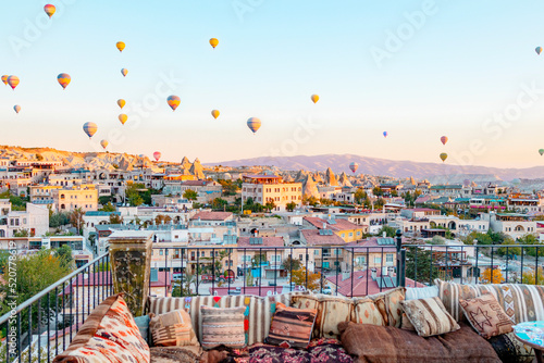 terrace of hotel in Goreme Cappadocia and hot air balloons rising into sky, concept of must see travel destination, bucket list trip