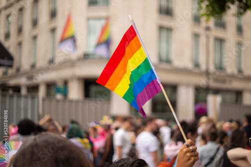 People taking part in LGBT parade, person holding rainbow flag