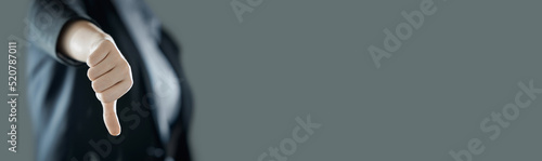 Female thumb down close-up on the background of suit in blur. Business concept. Photo with copy space.
