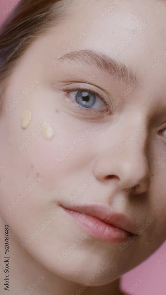 A young woman applying foundation with a dropper to her cheeks, close-up A young woman applying foundation with a dropper to her cheeks, close-up