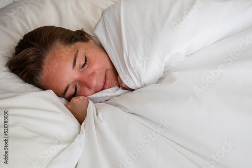 Tableau sur toile Mujer durmiendo plácidamente en cama con sábanas y frazadas blancas