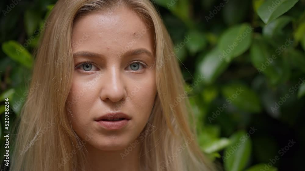 Young blonde woman looking at camera in forest, close-up Young blonde woman looking at camera in forest, close-up