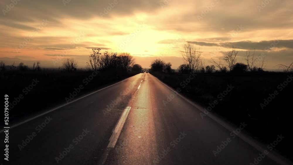 Kocani, Macedonia - 10 August, 2020: Open rural road through the green field and clouds on sunset sky in summer day, driver POV