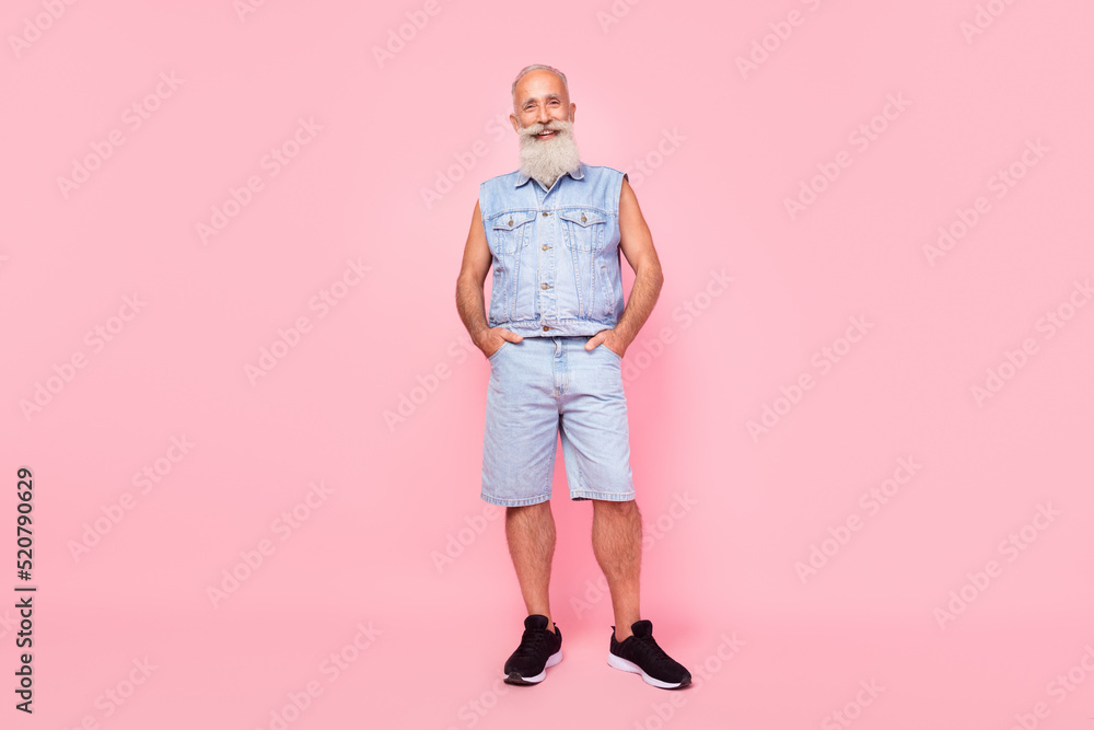 Full length photo of confident strong man pensioner dressed denim vest walking hands arms pockets isolated pink color background Full length photo of confident strong man pensioner dressed denim vest walking hands arms pockets isolated pink color background