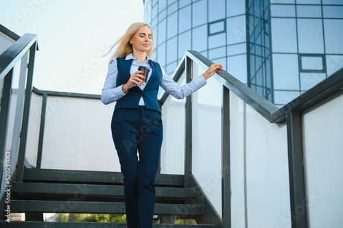 Beautiful Woman Going To Work With Coffee Walking Near Office Building. Portrait Of Successful Business Woman Holding Cup Of Hot Drink.