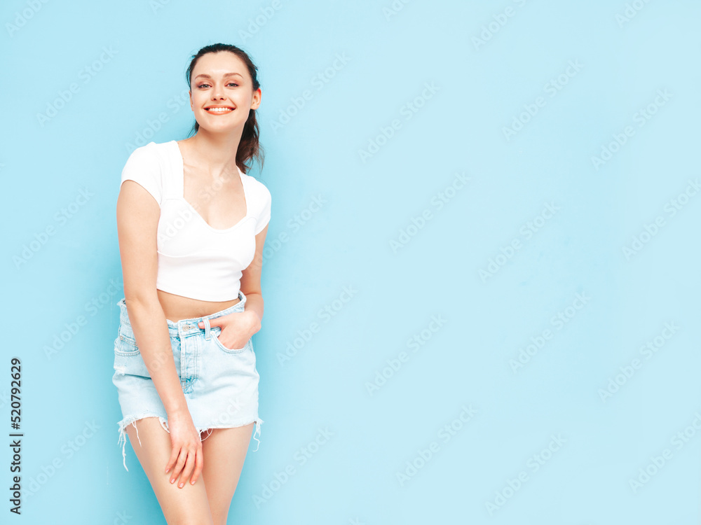 Young beautiful smiling female in trendy summer jeans skirt and top clothes. Sexy carefree woman posing near blue wall in studio. Positive brunette model having fun.Cheerful and happy Young beautiful smiling female in trendy summer jeans skirt and top clothes. Sexy carefree woman posing near blue wall in studio. Positive brunette model having fun.Cheerful and happy