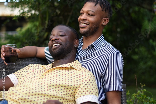 Photos USA, Louisiana, Smiling gay couple enjoying red wine on backyard