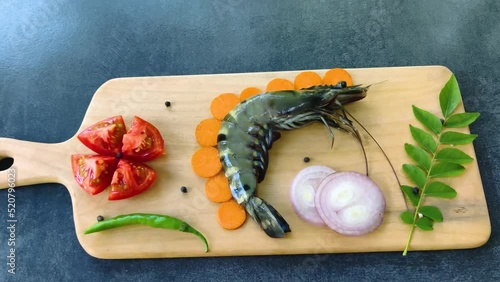 Fresh Giant Tiger Prawn decorated with herbs and vegetables on a wooden pad. photo