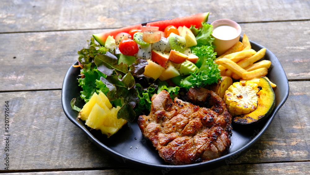 Fototapeta premium Grilled steaks pork with mixed fruit and green salad.