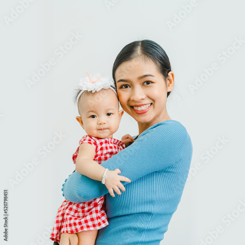 Canvas Print Looking to camera, Pretty Asian mom with baby daughter, Health care family love together