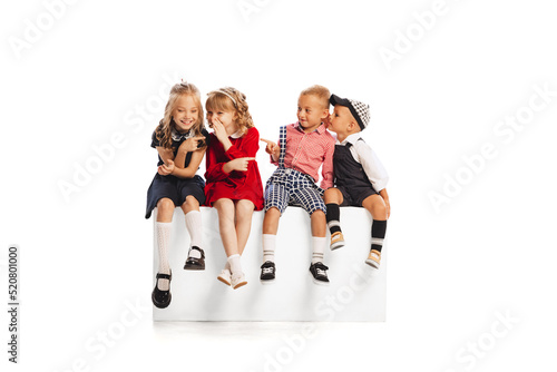 Portrait of children, boys and girls sitting together, whispering, giggling isolated over white studio background photo