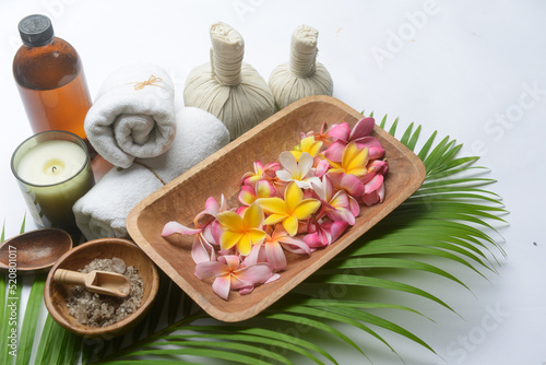 Spa setting with frangipaniand candle with green long leaves background