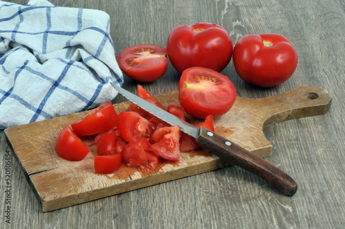 Tomates coupées en petits morceaux avec un couteau sur une planche à découper
