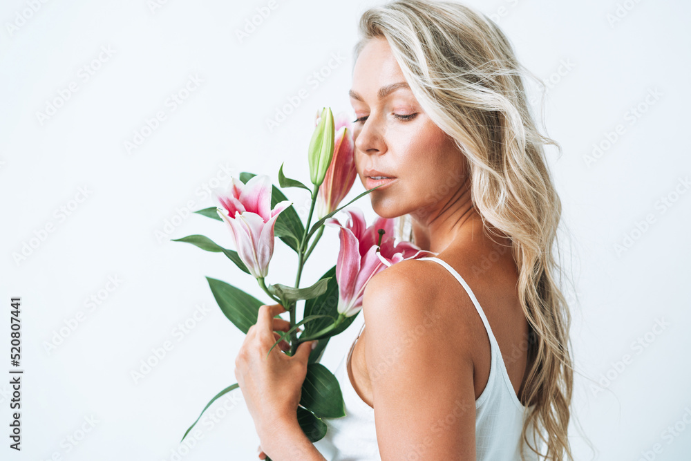 Beauty portrait of blonde hair smiling young woman with pink lily in hand isolated on white background Beauty portrait of blonde hair smiling young woman with pink lily in hand isolated on white background