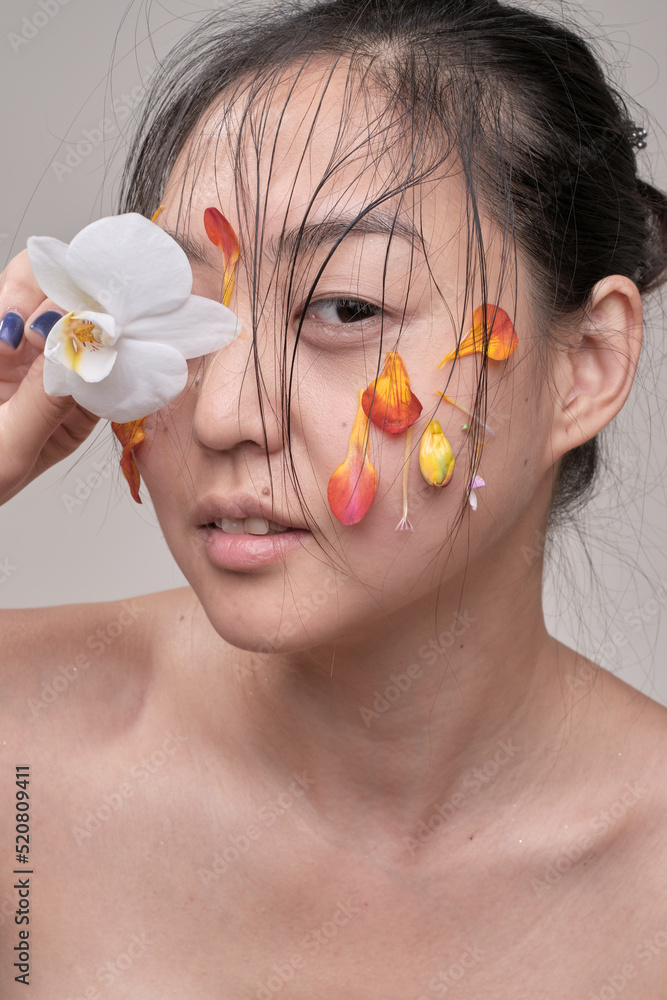 Attractive young Asian woman with flowers. Stunning brunette girl with flowers on the face. Close up face of young beautiful woman with a healthy clean skin. Pretty woman with floral makeup. Attractive young Asian woman with flowers. Stunning brunette girl with flowers on the face. Close up face of young beautiful woman with a healthy clean skin. Pretty woman with floral makeup.