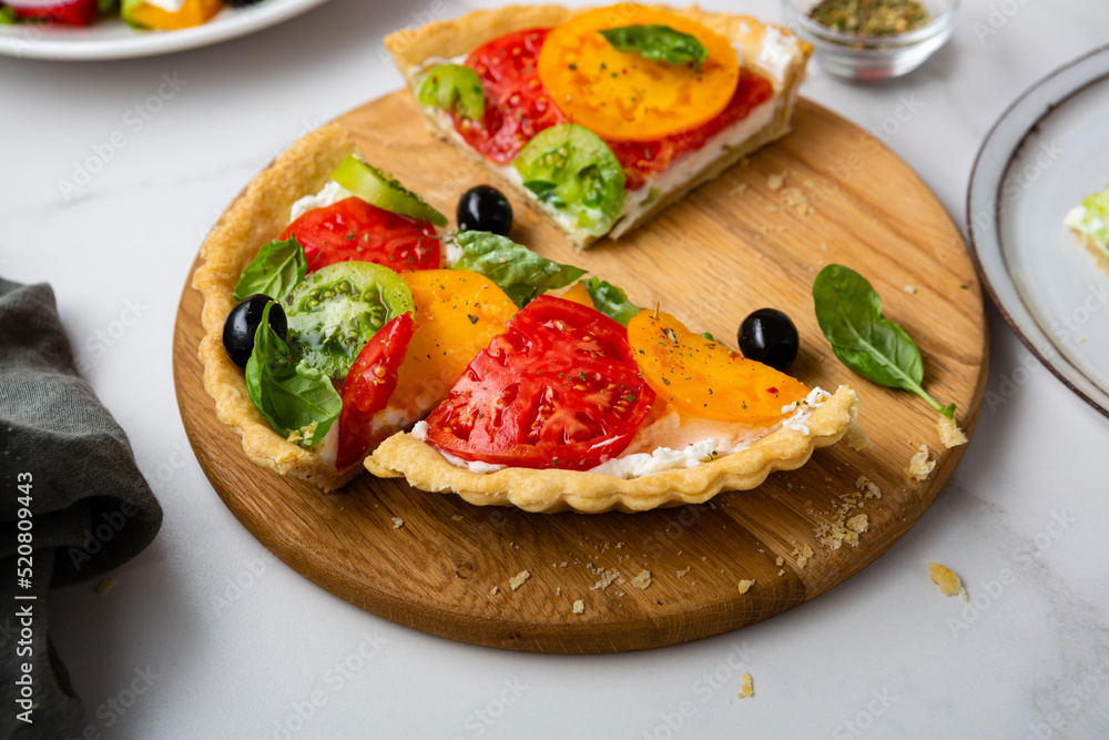 Close up of sliced quiche with cheese and tomatoes on kitchen board
