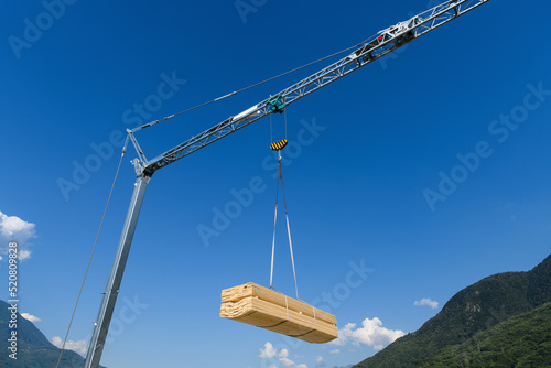 Construction crane  with hanging load of wood plank photo