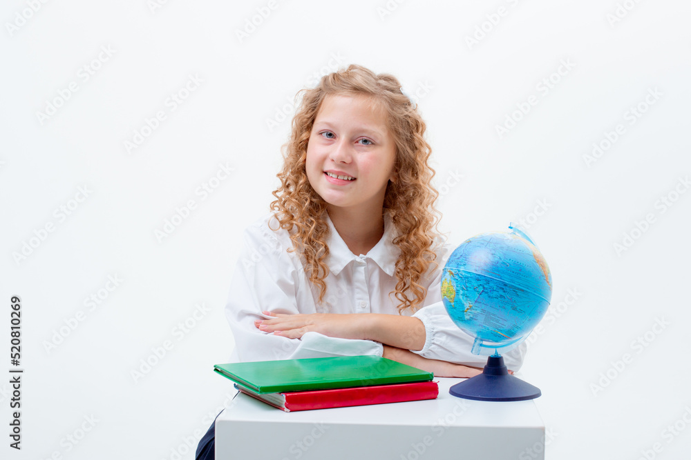 a teenage schoolgirl in a school uniform is sitting at a table with a book and a globe on a white background a teenage schoolgirl in a school uniform is sitting at a table with a book and a globe on a white background