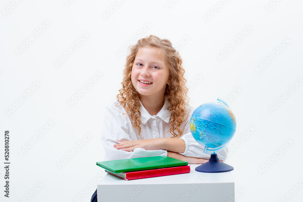 a teenage schoolgirl in a school uniform is sitting at a table with a book and a globe on a white background a teenage schoolgirl in a school uniform is sitting at a table with a book and a globe on a white background