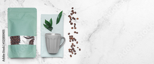 Coffee bags, cup and beans on light background with space for text
