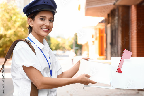 Young postwoman putting let...