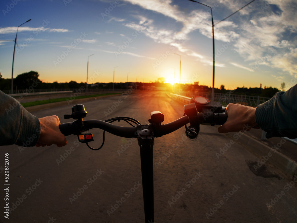 Pov, ride an electric scooter on the way to sunset. Modern electric urban transport Pov, ride an electric scooter on the way to sunset. Modern electric urban transport