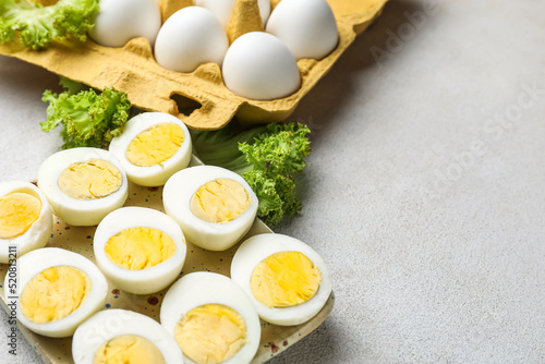 Plate with halves of boiled chicken eggs and lettuce on light background, closeup