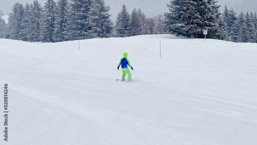Boy on snowboard ride downhill during strong snowfall Boy on snowboard ride downhill during strong snowfall