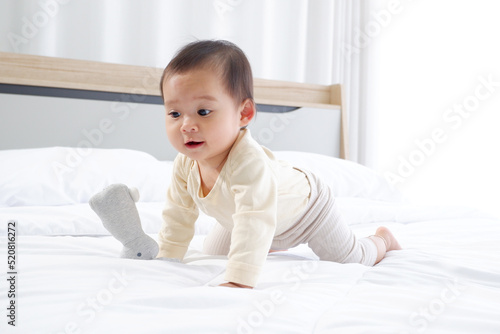 A cute little boy is sitting on a white mattress with a happy smile.