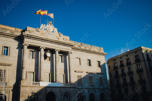 Casa de la Ciutat, City Hall of Barcelona on the Placa de Sant Jaume in The Gothic Quarter of Barcelona during a sunny summer evening with spanish and catalan flags photo