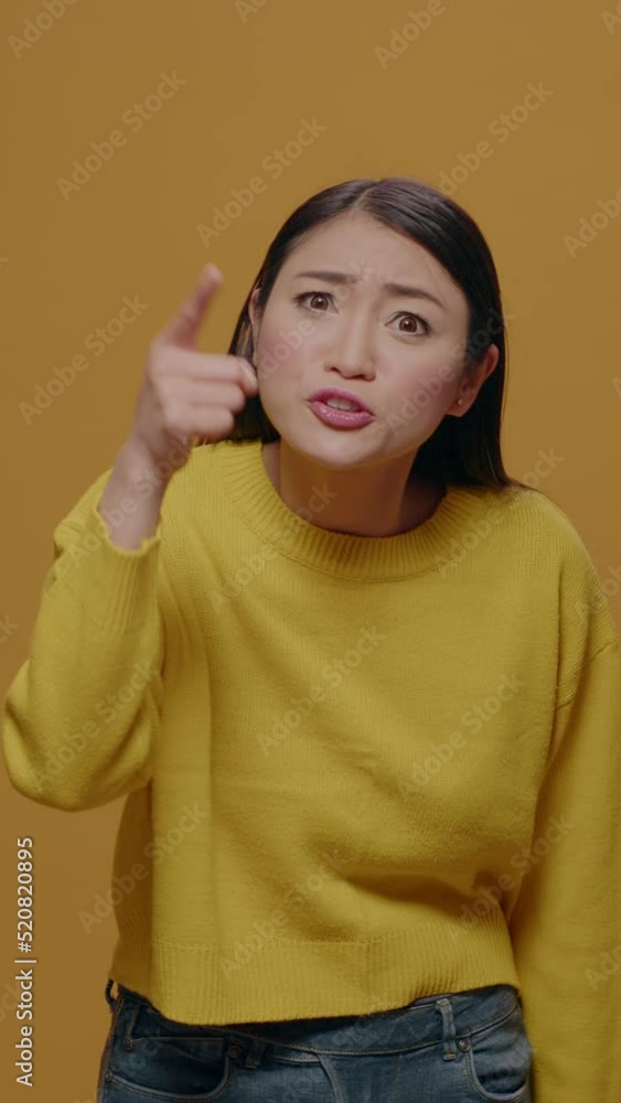 Vertical video: Angry woman showing index finger at camera and having argument, feeling furious and insulted in studio. Offended person arguing and having negative reaction, annoyed facial expression. Vertical video: Angry woman showing index finger at camera and having argument, feeling furious and insulted in studio. Offended person arguing and having negative reaction, annoyed facial expression.