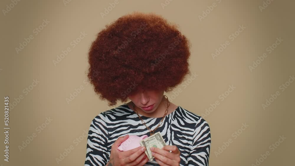 Poor pretty young woman insufficient amount of money, holding piggybank and one dollar banknote. Financial crisis. Bankruptcy. Poverty and destitution. Adult stylish girl on beige background indoors Poor pretty young woman insufficient amount of money, holding piggybank and one dollar banknote. Financial crisis. Bankruptcy. Poverty and destitution. Adult stylish girl on beige background indoors