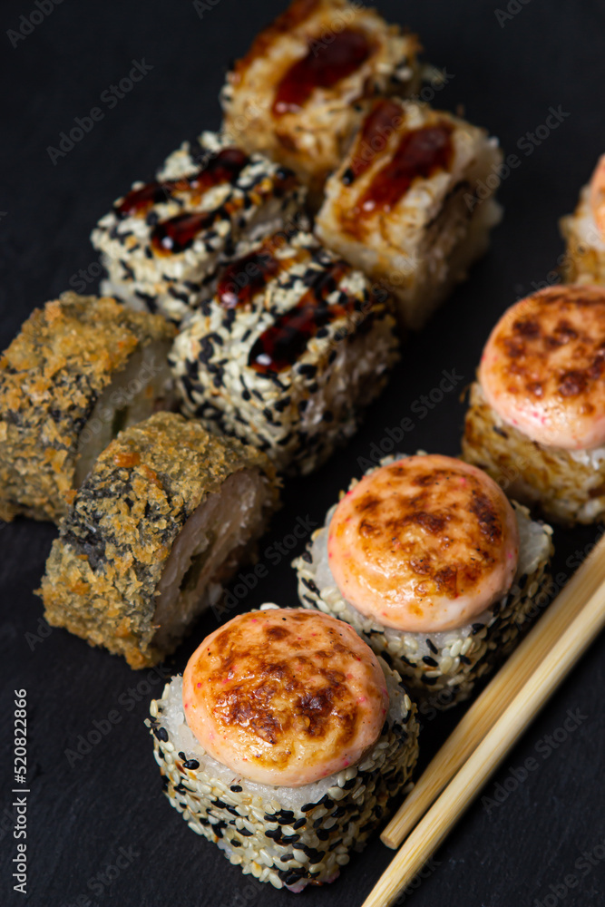 Rolls on a black background. Traditional Japanese food. Set of different types of rolls Rolls on a black background. Traditional Japanese food. Set of different types of rolls