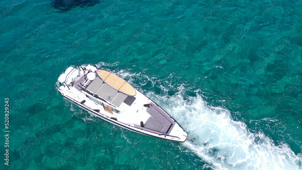 Aerial drone photo of small speed boat with dual outboards cruising in high speed deep blue Aegean sea